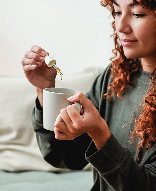 A woman holding a cup of coffee and spoon.